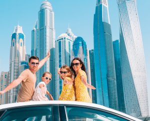Family summer vacation. Family of four on car vacation on background of skyscrapers in Dubai